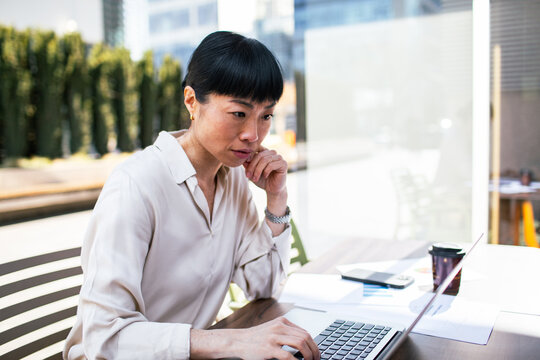 Focused businesswoman working on laptop at outdoor cafe