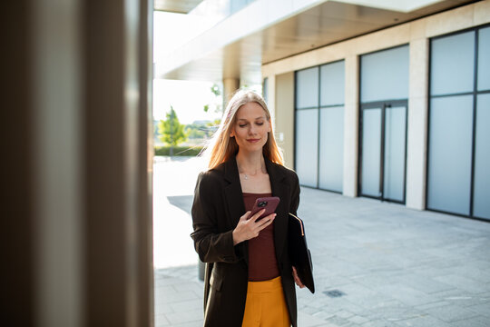Businesswoman using smartphone while walking outside office
