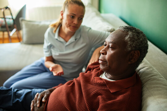 Caregiver comforting senior man on couch at home