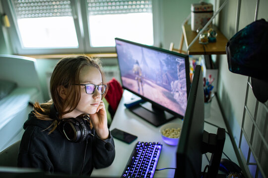 Teen gamer playing pc video game at home desk
