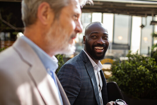 Two business colleagues smiling during outdoor coffee break