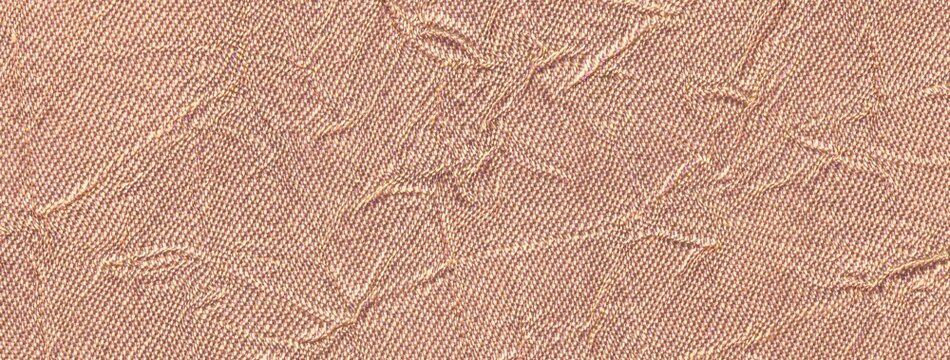 Light peach crumpled textured background from textile material. Wrinkled pastel coral fabric surface, macro