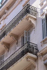 A perspective view of two elegant Art Nouveau balconies set against a clean white building façade...