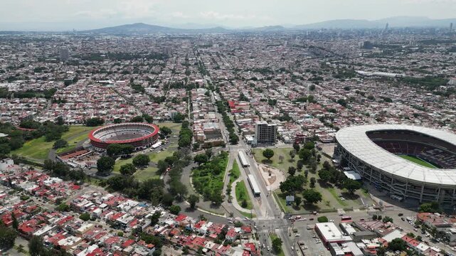 Drone's eye view of Guadalajara, Mexico, featuring Estadio Jalisco and Plaza de Toros Nuevo Progreso, with dense urban development.