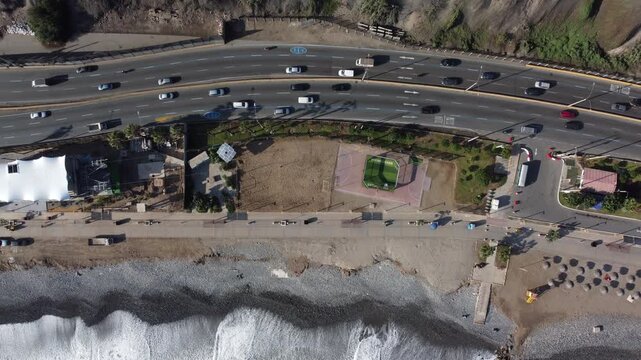 Aerial top down view of cars driving on the circuito de playas highway along the miraflores coast