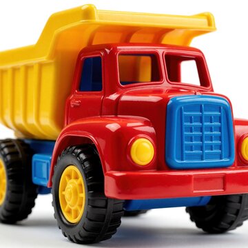 Red, yellow plastic toy dump truck with blue details. Colorful miniature construction vehicle for kids playtime. Small heavy machinery model sits on white background. Bright childhood toy used for