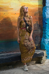 Mature woman laughing joyfully against a sunset-colored mural wall in Cartagena, embodying freedom and happiness while traveling. Wellbeing and vacation concept. © Gonzalo