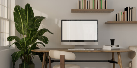 Minimalist home office workspace mockup with blank screen computer monitor on wooden table, bookshelf, and houseplant. © Pantira