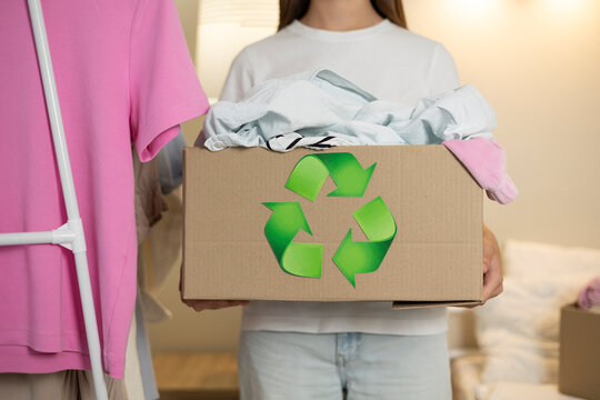 Teenage girl sorting used clothes for textile recycling and sustainable reuse at home, promoting responsible consumption.