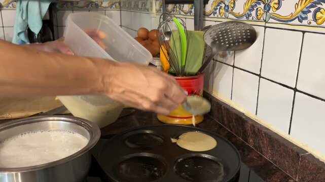 Manos vertiendo masa de pancakes en sart&eacute;n de cuatro cavidades