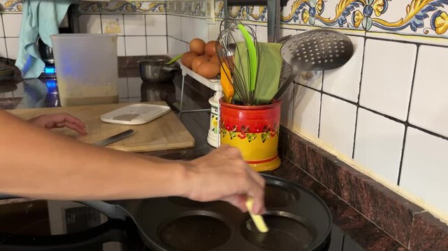 Manos untando mantequilla en sart&eacute;n de cuatro cavidades