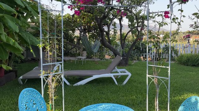 POV atravesando p&eacute;rgola hacia hamaca y tumbonas del jard&iacute;n