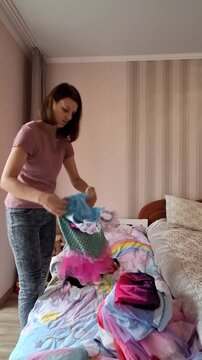 Woman organizing children's clothes in bedroom during daytime