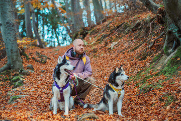 Man kneeling next to a husky in an autumn forest © iwavephoto
