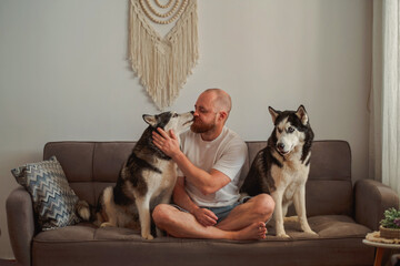 One husky licking its owner while the second waits © iwavephoto
