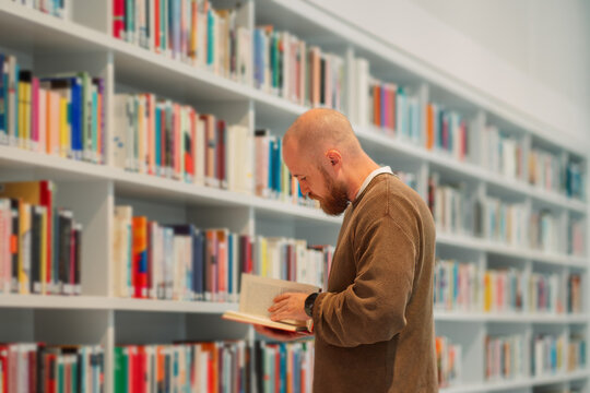 Man reading in a long aisle of a public library