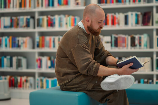 Man reading with a crossed leg on a library bench