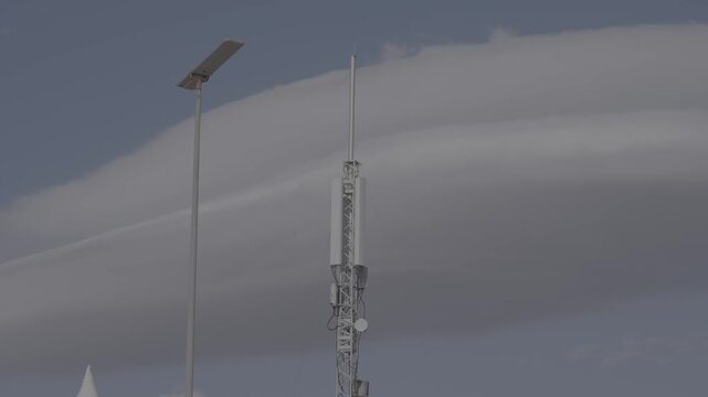Oran, Oran Province, Algeria - 29 May 2025: View of a telecommunications tower and a street light pole set against a dramatic lenticular cloud in the sky.