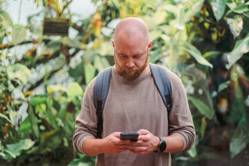 Fototapeta premium Man reading something on his phone inside a greenhouse
