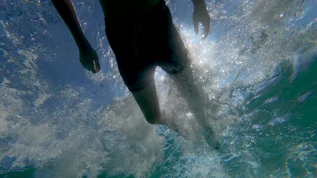 Teenage boy enjoys an active summer vacation by diving and swimming underwater in the sea with a mask.