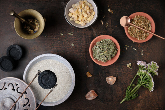 Incense ritual preparation with frankincense and dried herbs - placing the charcoal