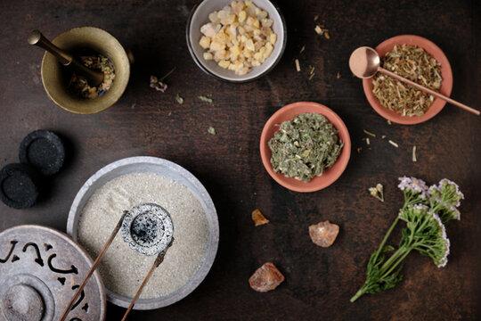 Incense ritual preparation with frankincense and dried herbs - placing the glowing charcoal