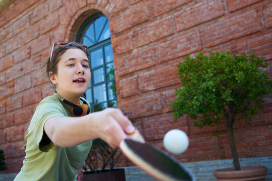 Teenager plays table tennis in a courtyard