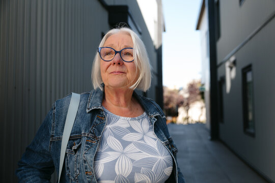 Confident senior woman outdoors wearing glasses and denim jacket