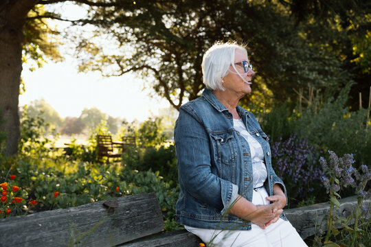 Candid portrait of a thoughtful senior woman enjoying a garden bench