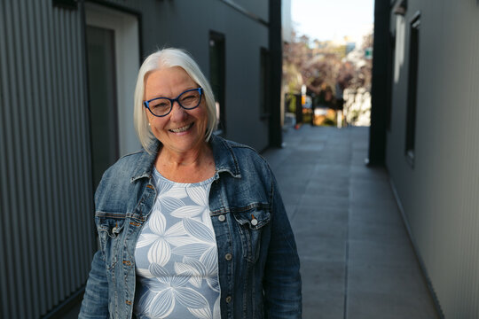 Senior woman smiling in denim jacket, candid outdoor portrait