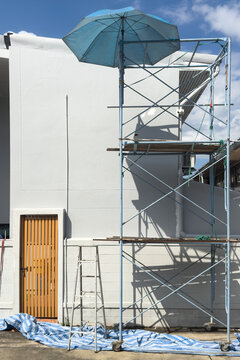 Scaffolding with a blue umbrella at a home improvement project 