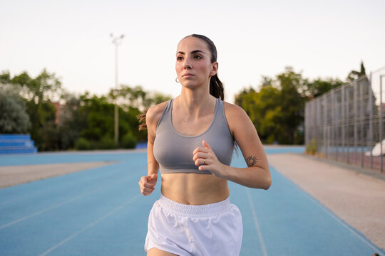 Young woman confidently running training on blue track