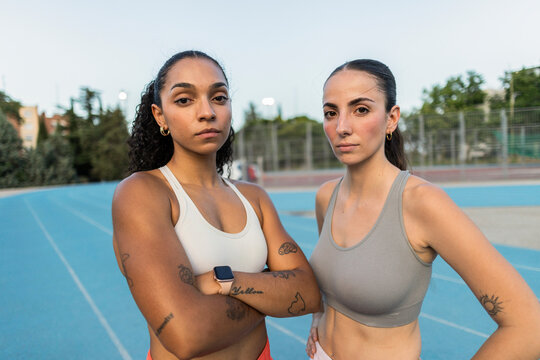 Two determined women athletes standing on running track