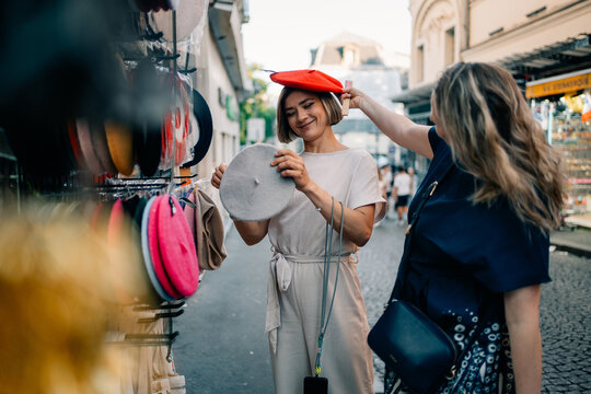 Friends Shopping for Hats in a Market During a Sunny Day