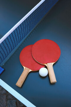 Two red table tennis paddles with a ball on a table