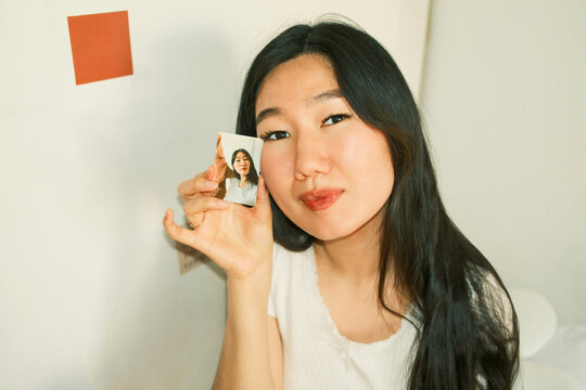 Young asian woman holding a finished instant photo of herself 