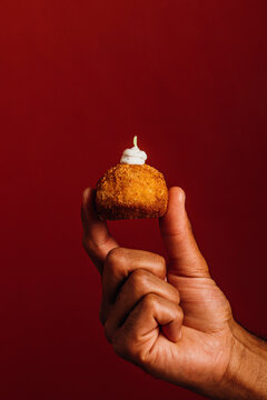 Hand holding a single crispy Spanish gourmet croquette 