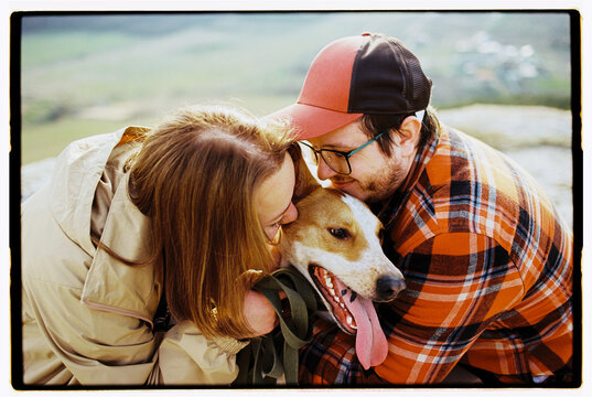 Close up film photo of happy couple hugging and cuddling their dog 