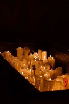 Rows of white prayer candles glowing in a dark temple