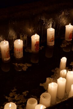 Prayer candles arranged on a dark surface at a temple