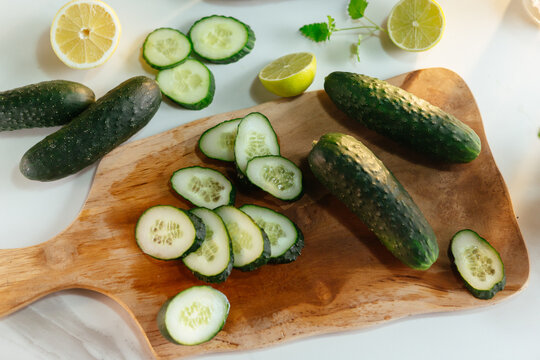 Fresh cucumber slices on wooden board with lemon