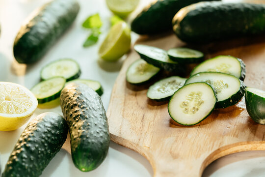 Fresh cucumbers slicing with lemon and lime on cutting board