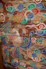 Fototapeta premium Painted phoenix and cloud motif on a wooden ceiling