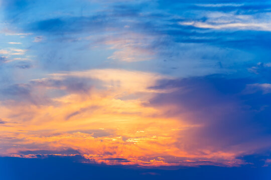 
Dramatic sunset glows beneath layered clouds, blending fiery orange and gold with deep blue skies. Luminous horizon creates a vivid, tranquil landscape

