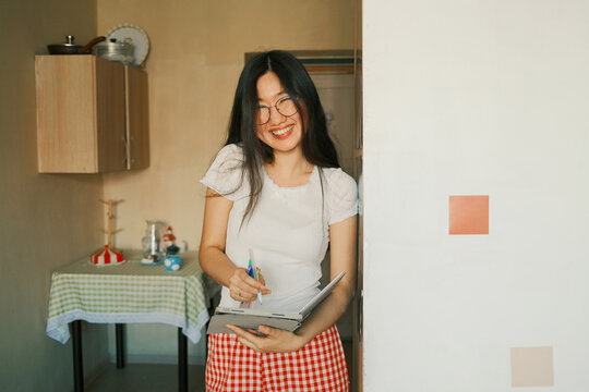 Happy young asian woman holding a tablet and planning at home
