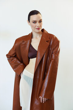 An elegant woman with striking blue eyes in chocolate leather coat.