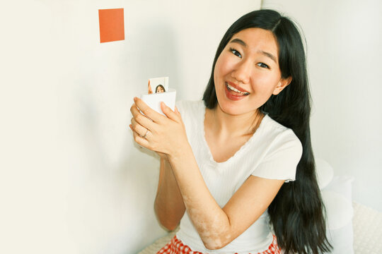 Happy young asian woman printing a photo on a portable printer