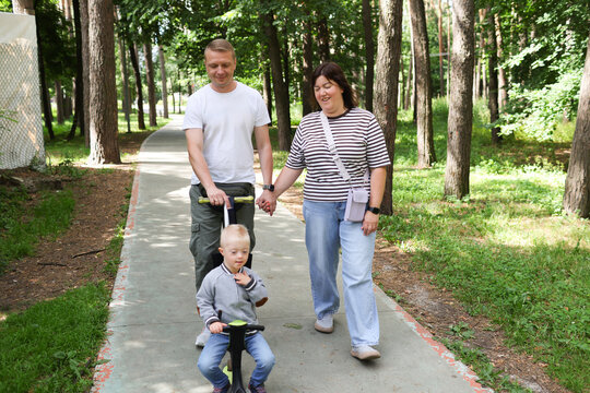 A family with a child with Down syndrome is walking in the park.