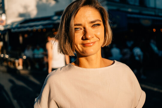 Woman Smiles on a Sunny Street During a Busy Day in the City