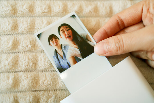 Hand holding an instant photo print with two women in the picture 